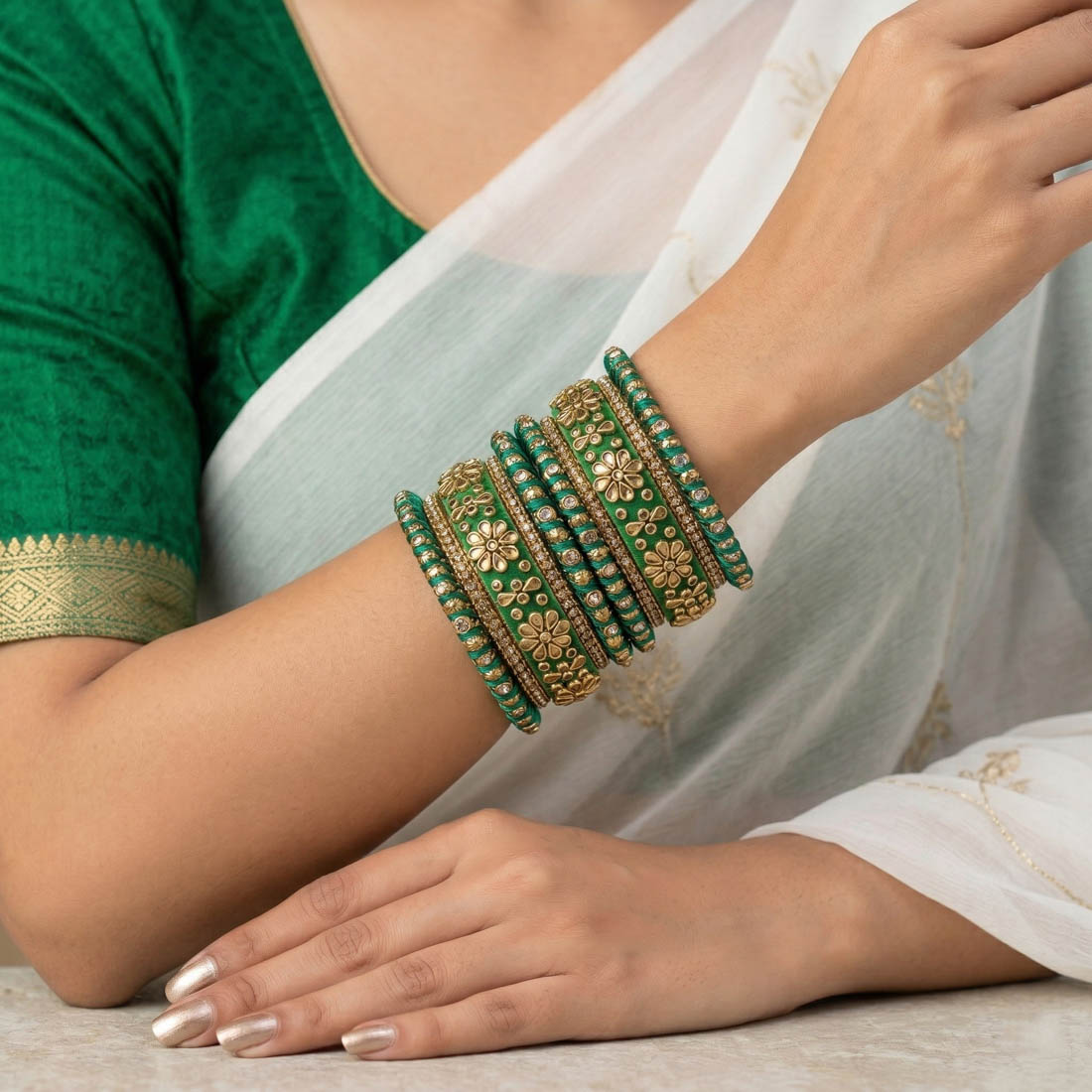 A royal green silk thread bridal bangle set adorned with intricate gold floral Kundan work, shimmering rhinestone chain borders, and textured metallic accents.