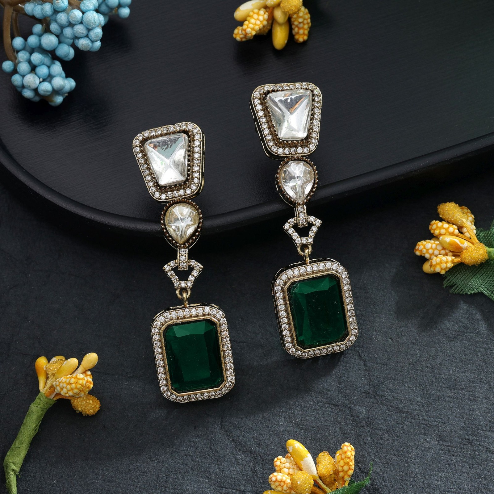 Pair of antique finish drop earrings featuring clear Monalisa stones and rectangular emerald-green drops embedded with American diamonds.