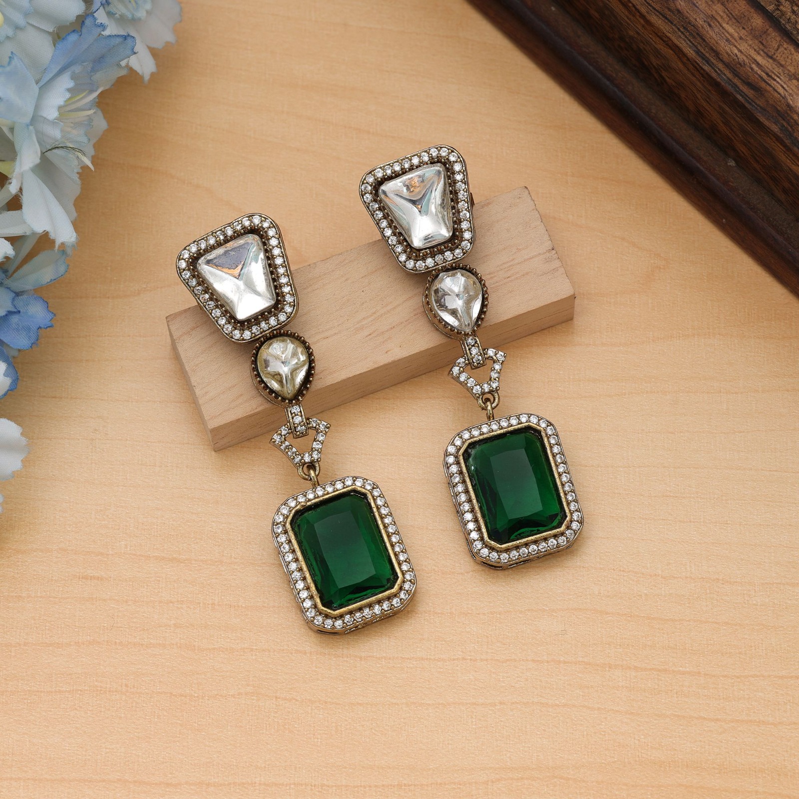 Pair of antique finish drop earrings featuring clear Monalisa stones and rectangular emerald-green drops embedded with American diamonds.